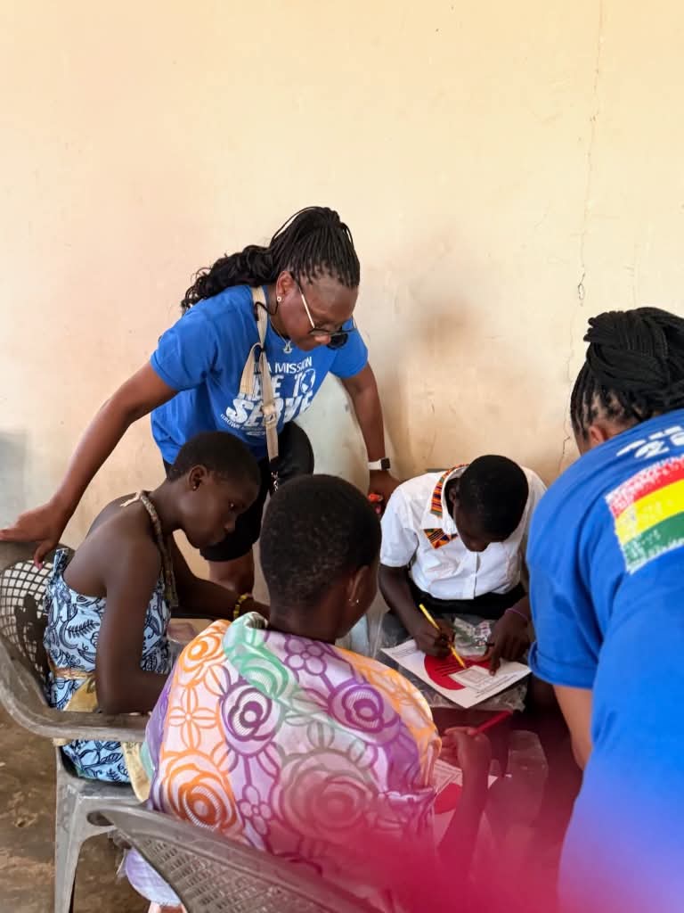 Volunteers in blue shirts working with children at a table