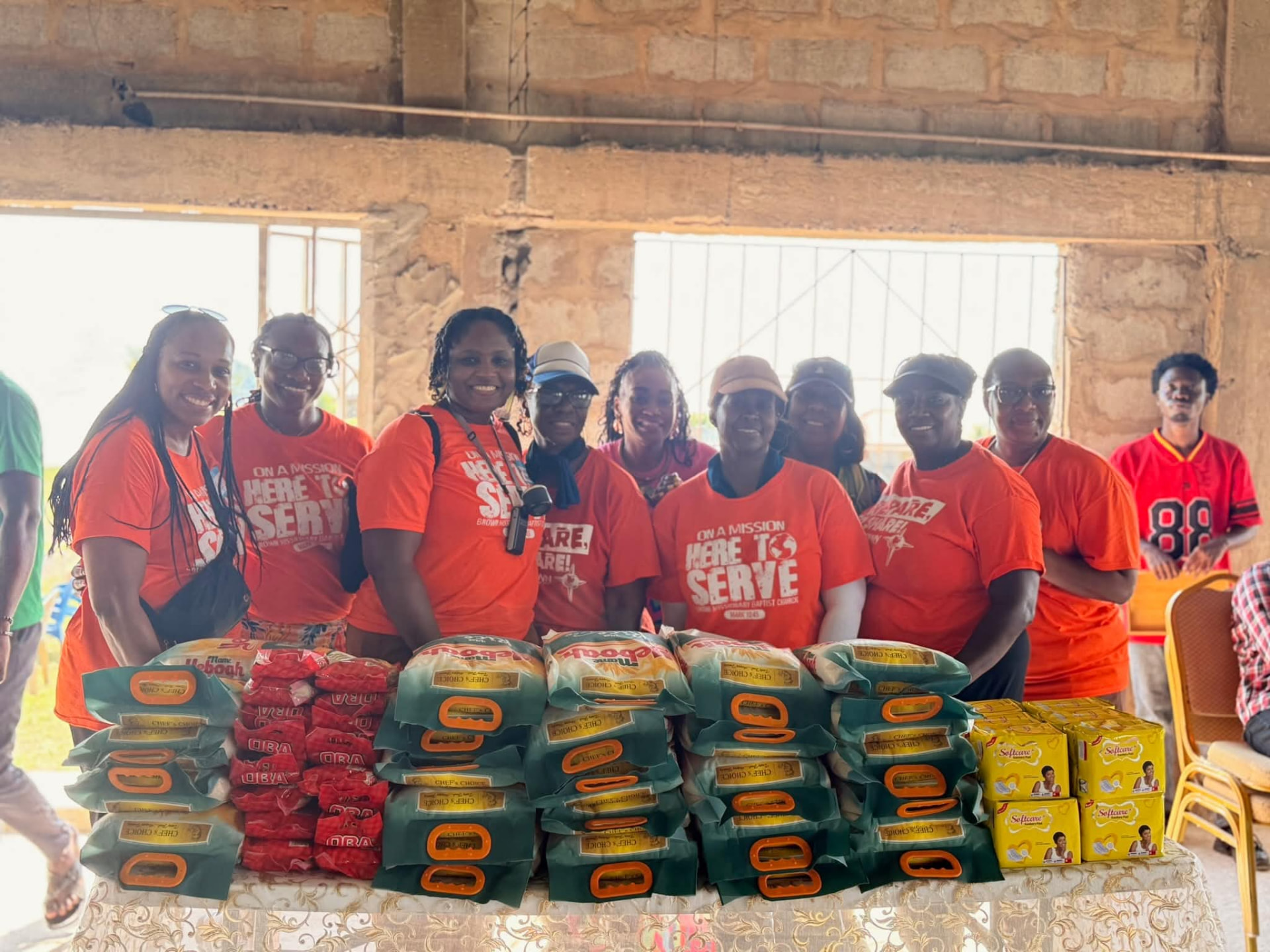 Volunteers in orange shirts behind donated food