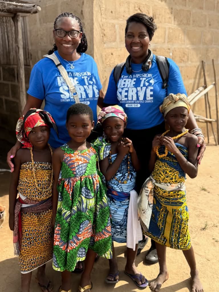 Two volunteers in blue mission shirts with four children