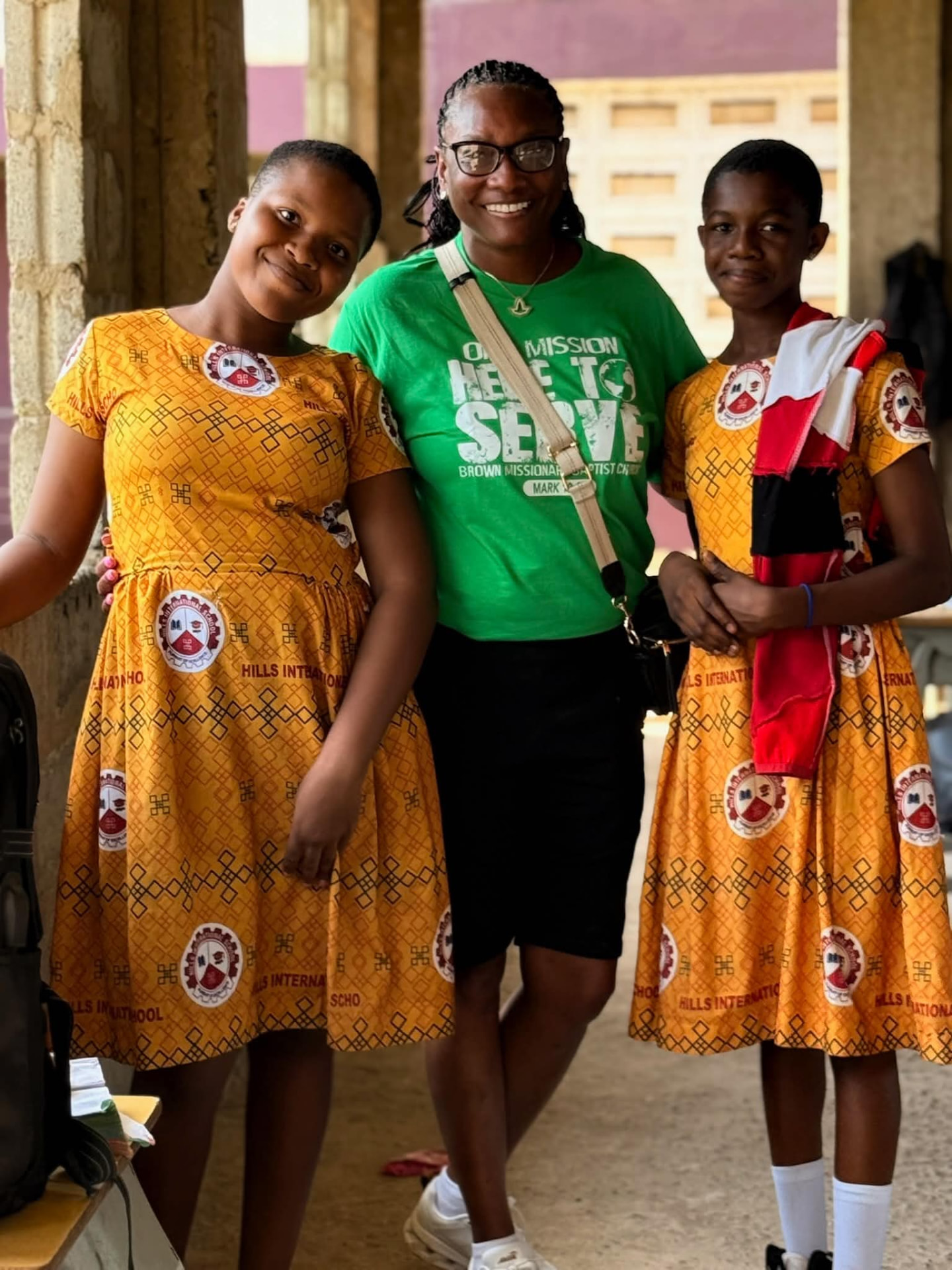 A volunteer in green with two students in yellow uniforms